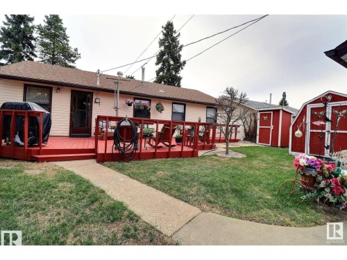 Rear view of house featuring a storage shed, a wooden deck, a yard, and roof with shingles - 8908 130 Avenue Nw, Edmonton, AB - Outdoor With Deck Patio Veranda