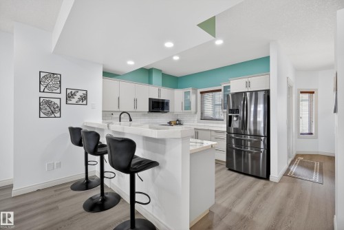 Kitchen featuring white cabinetry, stainless steel appliances, light wood-style floors, and a kitchen breakfast bar - 44 903 Rutherford Road, Edmonton, AB - Indoor Photo Showing Kitchen With Upgraded Kitchen