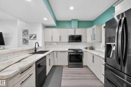 Kitchen featuring stainless steel appliances, a peninsula, light wood-style floors, light stone counters, and recessed lighting - 44 903 Rutherford Road, Edmonton, AB - Indoor Photo Showing Kitchen With Double Sink With Upgraded Kitchen