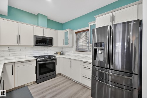 Kitchen featuring stainless steel appliances, light wood-type flooring, white cabinets, and glass insert cabinets - 44 903 Rutherford Road, Edmonton, AB - Indoor Photo Showing Kitchen With Upgraded Kitchen