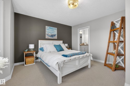 Bedroom with light carpet, a textured ceiling, and ensuite bath - 44 903 Rutherford Road, Edmonton, AB - Indoor Photo Showing Bedroom