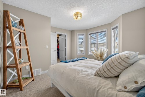 Carpeted bedroom featuring a textured ceiling and a walk in closet - 44 903 Rutherford Road, Edmonton, AB - Indoor Photo Showing Bedroom
