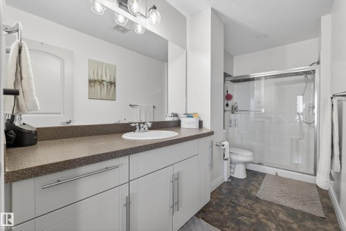 Bathroom featuring vanity, a shower stall, a textured ceiling, and stone finish floors - 44 903 Rutherford Road, Edmonton, AB - Indoor Photo Showing Bathroom