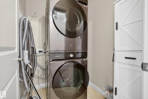 Laundry room featuring stacked washing machine and dryer and baseboards - 44 903 Rutherford Road, Edmonton, AB - Indoor Photo Showing Laundry Room