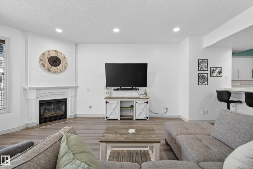 Living room with recessed lighting, wood finished floors, a textured ceiling, and a fireplace - 44 903 Rutherford Road, Edmonton, AB - Indoor Photo Showing Living Room With Fireplace