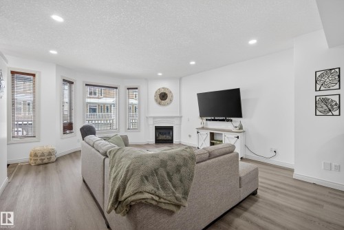 Living area featuring a textured ceiling, a fireplace, light wood-style floors, and recessed lighting - 44 903 Rutherford Road, Edmonton, AB - Indoor Photo Showing Living Room With Fireplace
