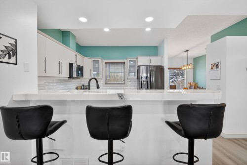 Kitchen featuring a breakfast bar area, a peninsula, white cabinetry, and stainless steel fridge with ice dispenser - 44 903 Rutherford Road, Edmonton, AB - Indoor Photo Showing Kitchen With Upgraded Kitchen