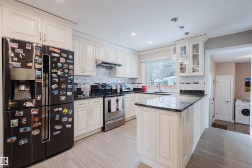 Kitchen featuring black fridge, dark stone counters, electric range, a peninsula, and glass fronted cabinets - 11519 37A Avenue, Edmonton, AB - Indoor Photo Showing Kitchen