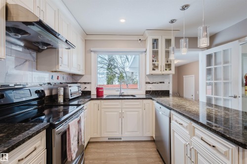 Kitchen featuring stainless steel appliances, extractor fan, light wood-style floors, and dark stone counters - 11519 37A Avenue, Edmonton, AB - Indoor Photo Showing Kitchen