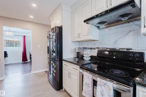 Kitchen featuring stainless steel electric range oven, ventilation hood, white cabinets, backsplash, and recessed lighting - 11519 37A Avenue, Edmonton, AB - Indoor Photo Showing Kitchen