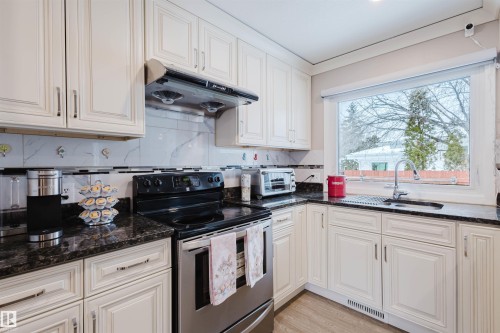 Kitchen featuring stainless steel electric stove, dark stone countertops, decorative backsplash, and light wood-style floors - 11519 37A Avenue, Edmonton, AB - Indoor Photo Showing Kitchen With Double Sink