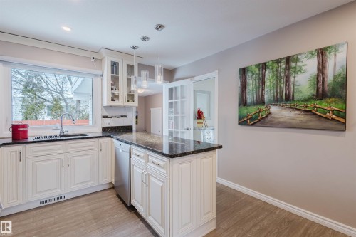 Kitchen with dark stone countertops, white cabinets, light wood finished floors, and glass fronted cabinets - 11519 37A Avenue, Edmonton, AB - Indoor Photo Showing Kitchen