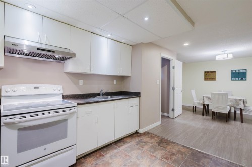 Kitchen with white electric range, dark countertops, white cabinets, recessed lighting, and stone finish floors - 11519 37A Avenue, Edmonton, AB - Indoor Photo Showing Kitchen