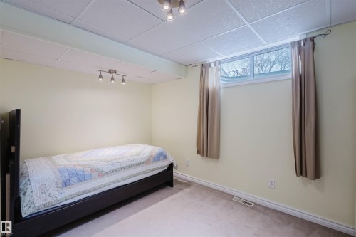 Carpeted bedroom featuring a paneled ceiling and track lighting - 11519 37A Avenue, Edmonton, AB - Indoor Photo Showing Bedroom