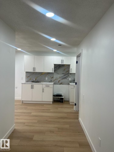 The kitchen features white cabinetry with modern hardware, a countertop, and a marble-patterned backsplash - 9194 Pear Drive Sw, Edmonton, AB - Indoor Photo Showing Kitchen
