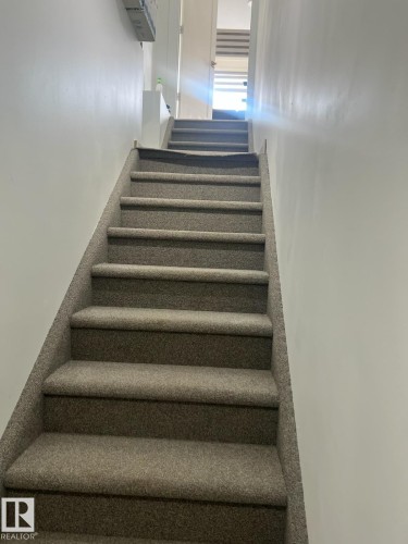 The property features a staircase with carpeted steps and white walls - 9194 Pear Drive Sw, Edmonton, AB - Indoor Photo Showing Other Room