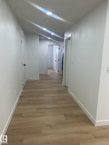 Well-lit hallway featuring light wood flooring and white walls - 9194 Pear Drive Sw, Edmonton, AB - Indoor Photo Showing Other Room