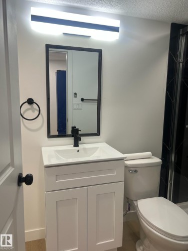 This bathroom features a contemporary white vanity with a rectangular sink and a matte black faucet - 9194 Pear Drive Sw, Edmonton, AB - Indoor Photo Showing Bathroom