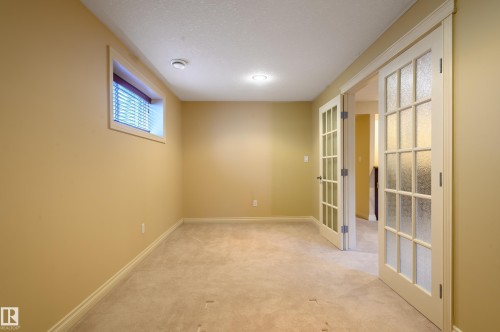 Spare room featuring light colored carpet and french doors - 48 Fairway Point(E), Spruce Grove, AB - Indoor Photo Showing Other Room