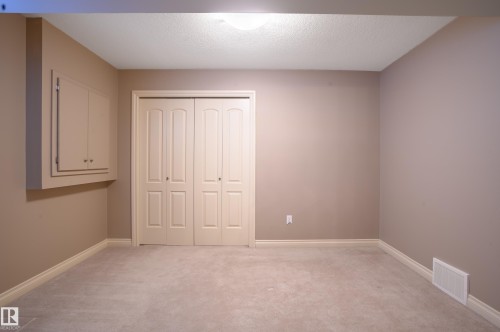 Unfurnished bedroom featuring light carpet, a closet, and a textured ceiling - 48 Fairway Point(E), Spruce Grove, AB - Indoor Photo Showing Other Room
