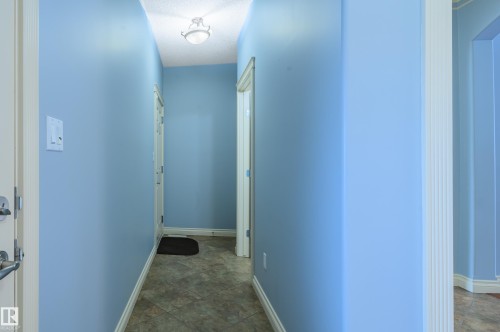 Hallway with a textured ceiling and stone finish floors - 48 Fairway Point(E), Spruce Grove, AB - Indoor Photo Showing Other Room
