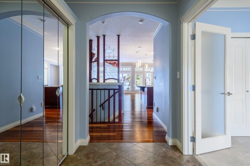 Hall with arched walkways, an upstairs landing, a textured ceiling, and dark wood-style flooring - 48 Fairway Point(E), Spruce Grove, AB - Indoor Photo Showing Other Room