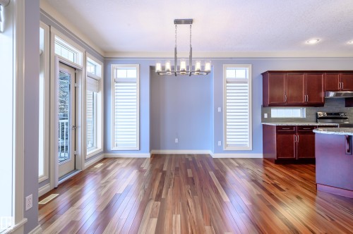 Kitchen featuring a chandelier, dark wood-style floors, stainless steel range with electric cooktop, light stone countertops, and decorative backsplash - 48 Fairway Point(E), Spruce Grove, AB - Indoor Photo Showing Kitchen