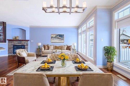 Dining room with dark wood finished floors and a fireplace in the open concept bungalow with tons of natural light this virtual photo is done for the benefit of how it could be furnished - 48 Fairway Point(E), Spruce Grove, AB - Indoor With Fireplace