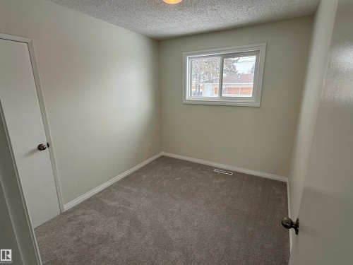 Spare room featuring dark colored carpet and a textured ceiling - 13323 68 Street, Edmonton, AB - Indoor Photo Showing Other Room