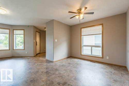 Empty room featuring stone finish flooring, ceiling fan, and healthy amount of natural light - 4827 54 Avenue, Wetaskiwin, AB - Indoor Photo Showing Other Room