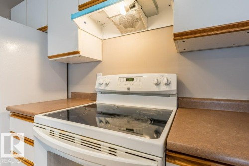 Kitchen featuring white electric range oven, ventilation hood, and white cabinets - 4827 54 Avenue, Wetaskiwin, AB - Indoor Photo Showing Kitchen