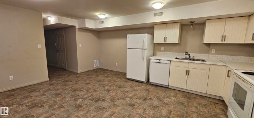 Kitchen featuring stone finish floors, white appliances, light countertops, light wood finish cabinets, and cream cabinetry - 4827 54 Avenue, Wetaskiwin, AB - Indoor Photo Showing Kitchen With Double Sink
