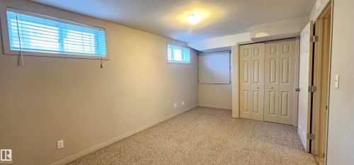 Unfurnished bedroom featuring a textured ceiling, light colored carpet, and a closet - 4827 54 Avenue, Wetaskiwin, AB - Indoor Photo Showing Other Room