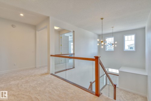 Hall with light carpet, hanging lights, a textured ceiling, and an upstairs landing - 8320 Mayday Link Sw, Edmonton, AB - Indoor Photo Showing Other Room