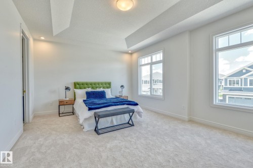 Bedroom featuring light carpet, a textured ceiling, recessed lighting, and a tray ceiling - 8320 Mayday Link Sw, Edmonton, AB - Indoor