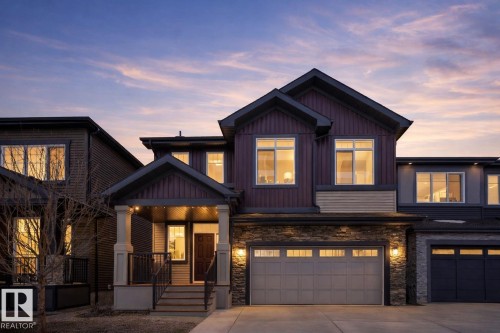 Craftsman-style home featuring a porch, concrete driveway, a garage, and stone siding - 8320 Mayday Link Sw, Edmonton, AB - Outdoor