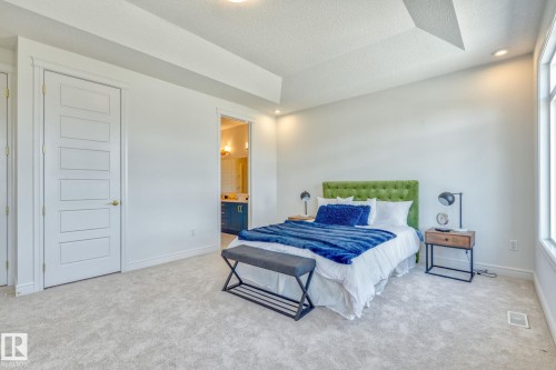 Bedroom with light carpet, a raised ceiling, recessed lighting, ensuite bath, and a textured ceiling - 8320 Mayday Link Sw, Edmonton, AB - Indoor Photo Showing Bedroom