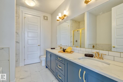 Full bath featuring double vanity, a marble finish shower, and light marble finish flooring - 8320 Mayday Link Sw, Edmonton, AB - Indoor Photo Showing Bathroom
