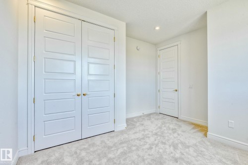Unfurnished bedroom with light colored carpet, a closet, a textured ceiling, and recessed lighting - 8320 Mayday Link Sw, Edmonton, AB - Indoor Photo Showing Other Room