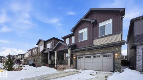 Craftsman inspired home featuring stone siding, an attached garage, and a residential view - 8320 Mayday Link Sw, Edmonton, AB - Outdoor With Facade