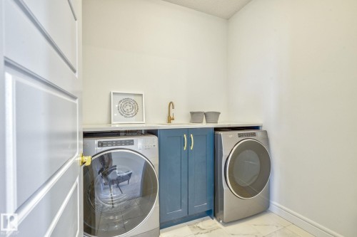 Laundry room with independent washer and dryer, light marble finish floors, and a textured ceiling - 8320 Mayday Link Sw, Edmonton, AB - Indoor Photo Showing Laundry Room