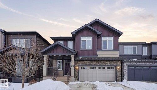Craftsman-style home featuring an attached garage, stone siding, and driveway - 8320 Mayday Link Sw, Edmonton, AB - Outdoor With Facade