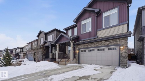 Craftsman inspired home with an attached garage, stone siding, and a residential view - 8320 Mayday Link Sw, Edmonton, AB - Outdoor With Facade