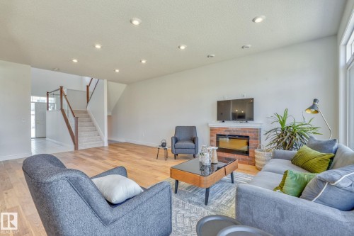 Living area featuring light wood-style flooring, a fireplace, a textured ceiling, and recessed lighting - 8320 Mayday Link Sw, Edmonton, AB - Indoor Photo Showing Living Room With Fireplace