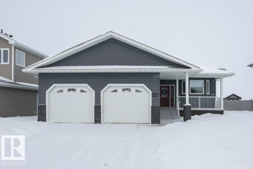 View of front of property featuring covered porch, stone siding, and an attached garage - 11116 103 Street, Westlock, AB - Outdoor
