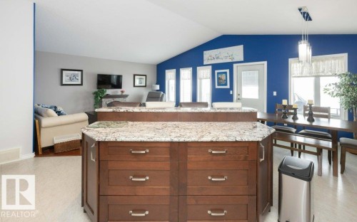 Kitchen with open floor plan, a kitchen island, light stone counters, and hanging light fixtures - 11116 103 Street, Westlock, AB - Indoor
