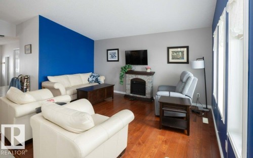 Living room with a stone fireplace and wood finished floors - 11116 103 Street, Westlock, AB - Indoor Photo Showing Living Room