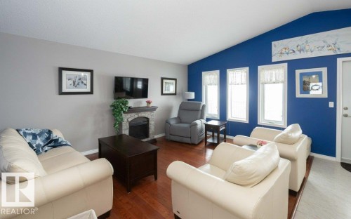 Living room featuring a fireplace, wood finished floors, and vaulted ceiling - 11116 103 Street, Westlock, AB - Indoor Photo Showing Living Room