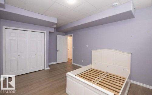 Unfurnished bedroom featuring dark wood finished floors, a paneled ceiling, and a closet - 11116 103 Street, Westlock, AB - Indoor