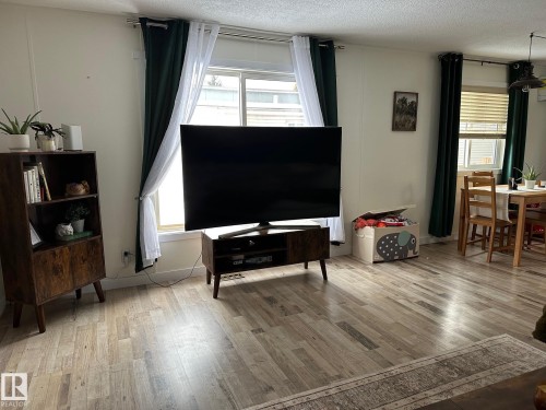 Living area featuring light wood-style flooring and a textured ceiling - 341 West Brook Way Nw, Edmonton, AB - Indoor